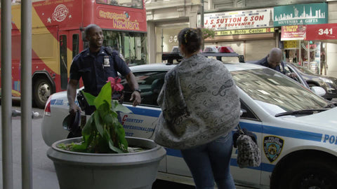 smiling African American police officer taking picture with happy white tourist woman in front of cop car