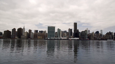 panning Manhattan skyline across East River water - reflection of skyscrapers in 4K NYC