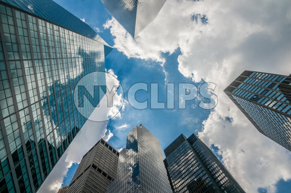 corporate office buildings - upward angle of glass window skyscrapers over blue sky on sunny summer day in Manhattan