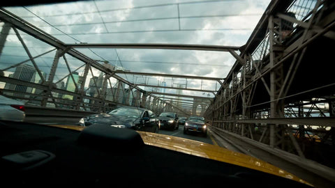 taxi interior rear windshield crossing Brooklyn Bridge on cloudy day in NYC