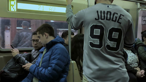 yankee fan in Aaron Judge 99 jersey interior subway R train carriage riding in New York City NYC