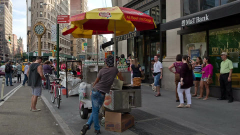 hot dog vendor on summer day in Flatiron District with 5th Ave clock on sunny day in Manhattan NYC