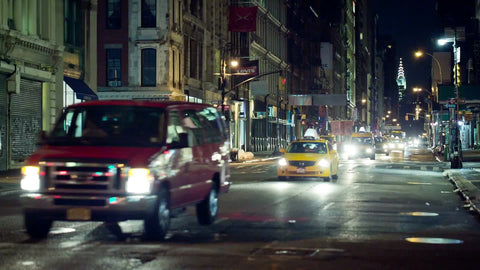 taxi cabs driving in traffic down Broadway in SoHo at night with Chrysler Building in background in NYC