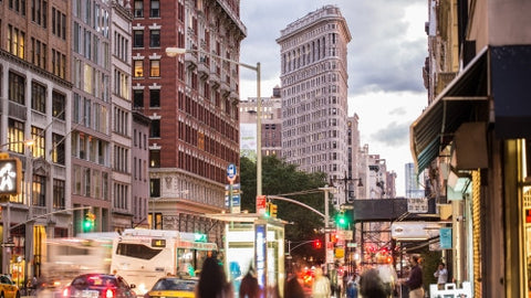 Flatiron Building on 5th Ave in late afternoon early evening with street and traffic lights in Manhattan summer