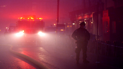 FDNY firetruck with NYPD police officer standing on street with smoke at night - 4k in New York City