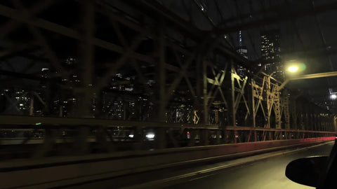 crossing the Brooklyn Bridge - driving across with Freedom Tower Manhattan skyline view at night New York City NYC