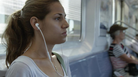closeup of beautiful woman's face listening to earbuds while riding moving subway - elevated train during day - contact us for model details