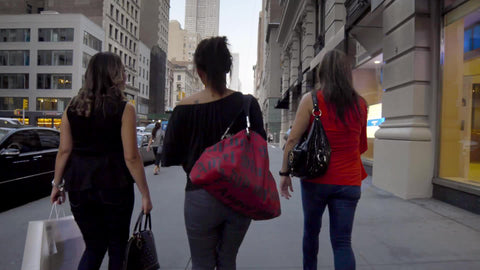 three women walking on 5th Avenue with Empire State Building overhead on summer day