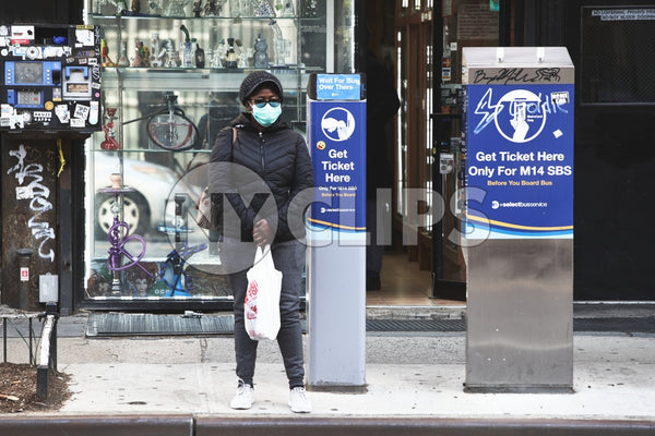 woman in mask during covid pandemic with shopping bag on sidewalk NYC