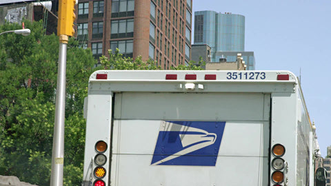 USPS United States Parcel Service truck driving with Empire State Building in background - mail delivery driving in Manhattan New York City NYC
