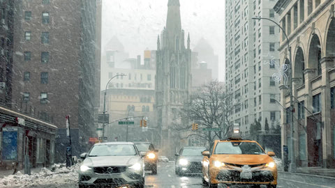 snowing on taxicab and cars waiting at traffic light in blizzard Grace Church snow in Manhattan New York City NYC