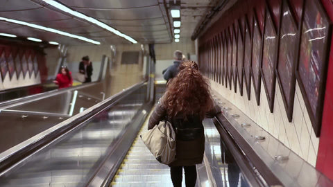 woman riding escalator alone in subway station - rear shot of lady heading downstairs 1080 HD in NYC