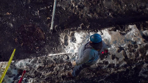 worker moving fiber optic cables at night in now on street
