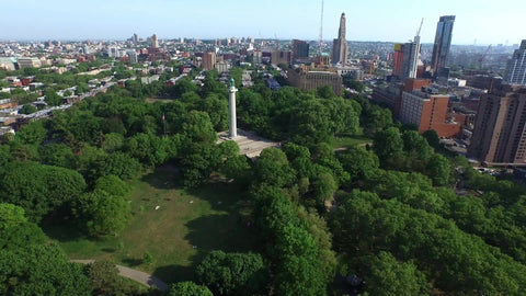 moving in aerial shot of Prison Ships Martyrs' Monument at Fort Greene Park in Brooklyn with trees on sunny day