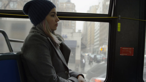 woman on bus - passenger riding MTA public transportation - hat and coat in winter on gloomy gray day  - 4K slow motion New York City