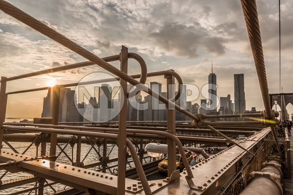 steel beams of Brooklyn Bridge close-up with Manhattan skyline in background at sunset in NYC