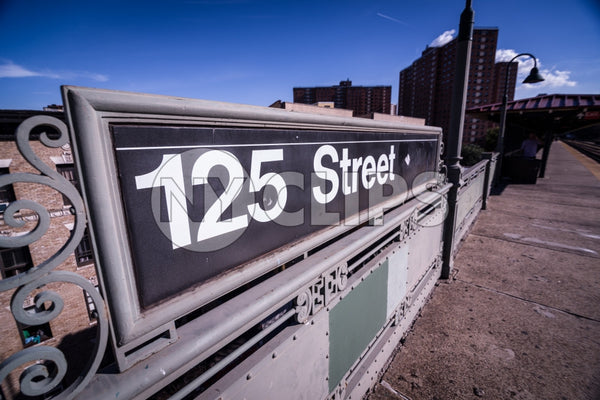 125th street sign in Uptown Manhattan with projects in background in NYC