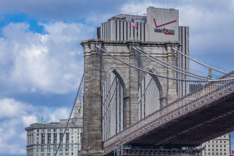 Brooklyn Bridge close-up with American flag and Verizon Building in background in NYC