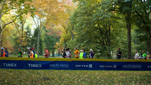far shot of marathon runners in Central Park in spring with beautiful colorful changing leaves on trees 1080 HD in NYC