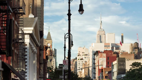 Greenwich Village in Manhattan on summer day, people walking with Empire State Building and Jefferson Market Library clock tower in background