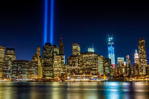September 11th memorial beams on 911 over Manhattan skyline with Freedom Tower in red white and blue color lights