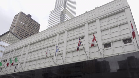 Bloomingdale's department store in Midtown Manhattan - tilting down from flags to street with cars, taxis in traffic in 4K and 1080 HD in NYC