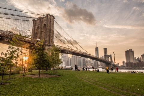 Brooklyn Bridge Park with people enjoying sunset with Manhattan skyline across East River in NYC summer