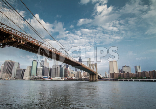 Brooklyn Bridge with Manhattan skyline in background across East River water during day in NYC