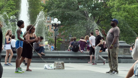 woman with double-dutch skills in Washington Square Park on summer day with sprinkler in background in NYC