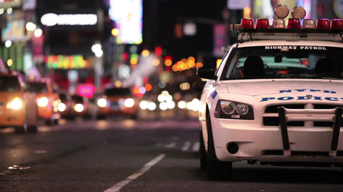 police car in Midtown Manhattan at night - Times Square lights in background with NYPD vehicle parked in NYC