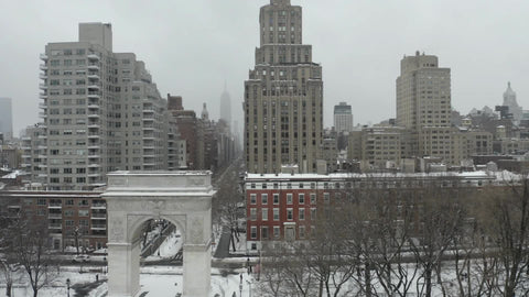 lateral aerial of Washington Square Park arch white winter snow - blizzard snowing in NYC
