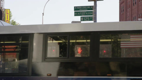 125th Street sign in Harlem with bus passing on corner, uptown NYC