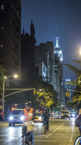 Empire State Building at night from Lower 5th Ave with bicycle delivery boy riding bike with helmet