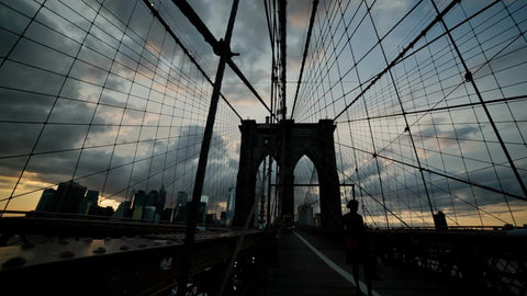 Brooklyn Bridge at sunset in early evening with people crossing - silhouette in NYC