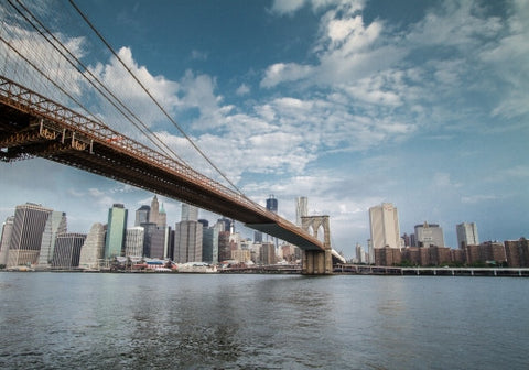 Brooklyn Bridge with Manhattan skyline in background across East River water during day in NYC