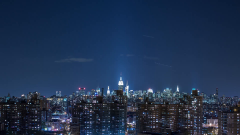 nighttime timelapse of Manhattan skyline with Empire State Building and clouds floating by - 4K at night