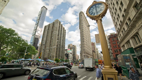 famous 5th Ave clock with Flatiron Building skyscraper in Manhattan - summer day