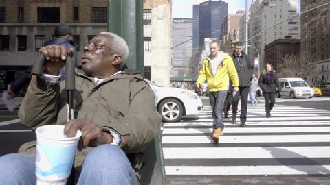 homeless elderly black man shaking cup on street with MetLife Building in background - 4K and 1080 HD in NYC