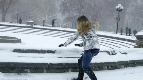 girl throwing snow up in air in Washington Square Park - having fun in winter blizzard snowstorm - snowing in slow motion