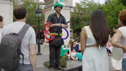 street performer making balloons for people in Washington Square Park on summer day in NYC