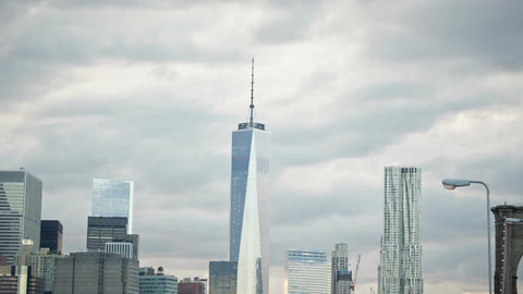 Orthodox Jew walking across Brooklyn Bridge on summer day with Freedom Tower and Manhattan skyscrapers in NYC