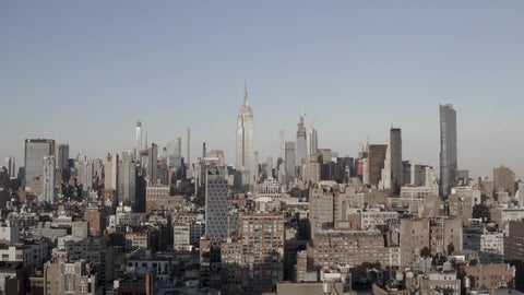 aerial pulling back from Manhattan cityscape with Empire State Building towering over buildings New York City NYC