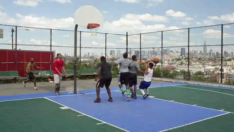 kids playing basketball on summer day - outdoor court with view of Empire State Building in NYC