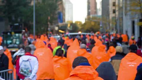 orange ponchos - people walking with backs after marathon in spring in NYC