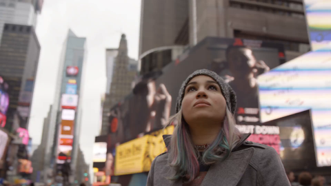 beautiful woman in hat looking up at Times Square signs and ads - bright lights are overwhelming for tourist - 4K slow motion