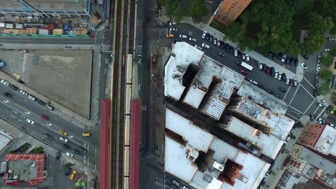 aerial of elevated 1 train on tracks passing through projects in Harlem