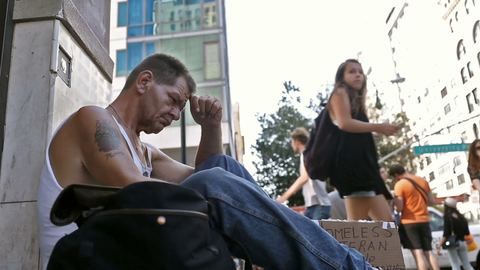 low view of homeless veteran sitting on sidewalk with sign - sad man in Union Square Manhattan New York City