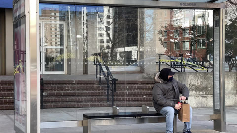 man at bus stop twisting soda bottle waiting with medical mask in Covid-19 winter Upper West Side Manhattan New York City NYC