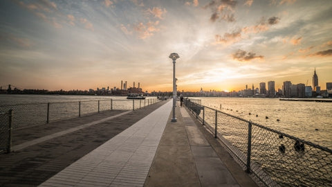 Manhattan skyline view from dock with fence in Brooklyn at sunset