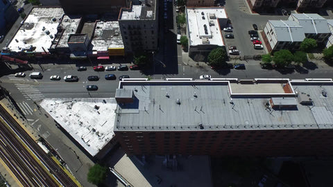 aerial over red brick building in the Bronx with elevated subway train tracks
